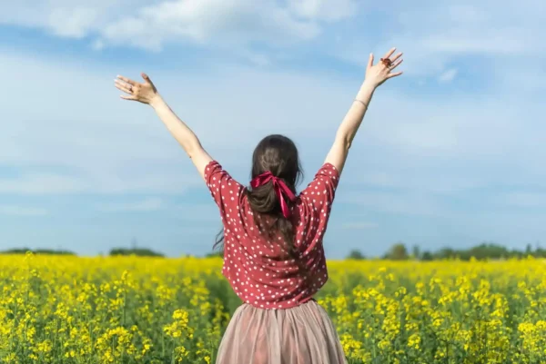 A woman with arms uplifted in a field, embodying the theme of transformation and meaningful change in psychology.