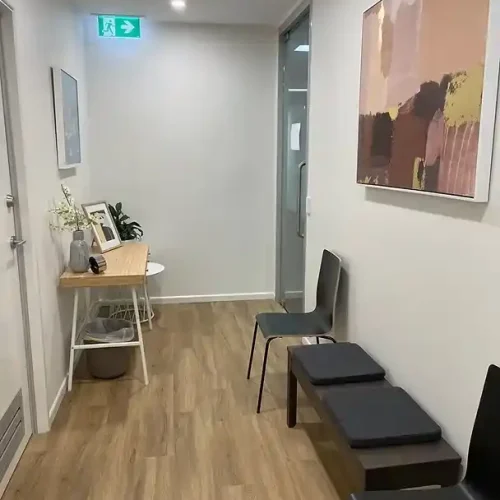 A cozy waiting room featuring several chairs and a colorful painting hanging on the wall.