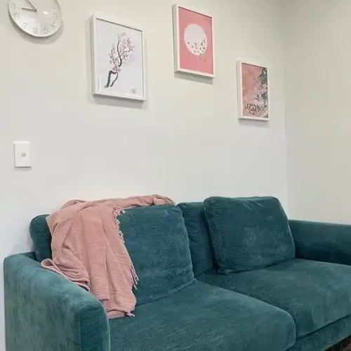 A teal couch in a room adorned with framed pictures on the walls, creating a cozy and inviting atmosphere.